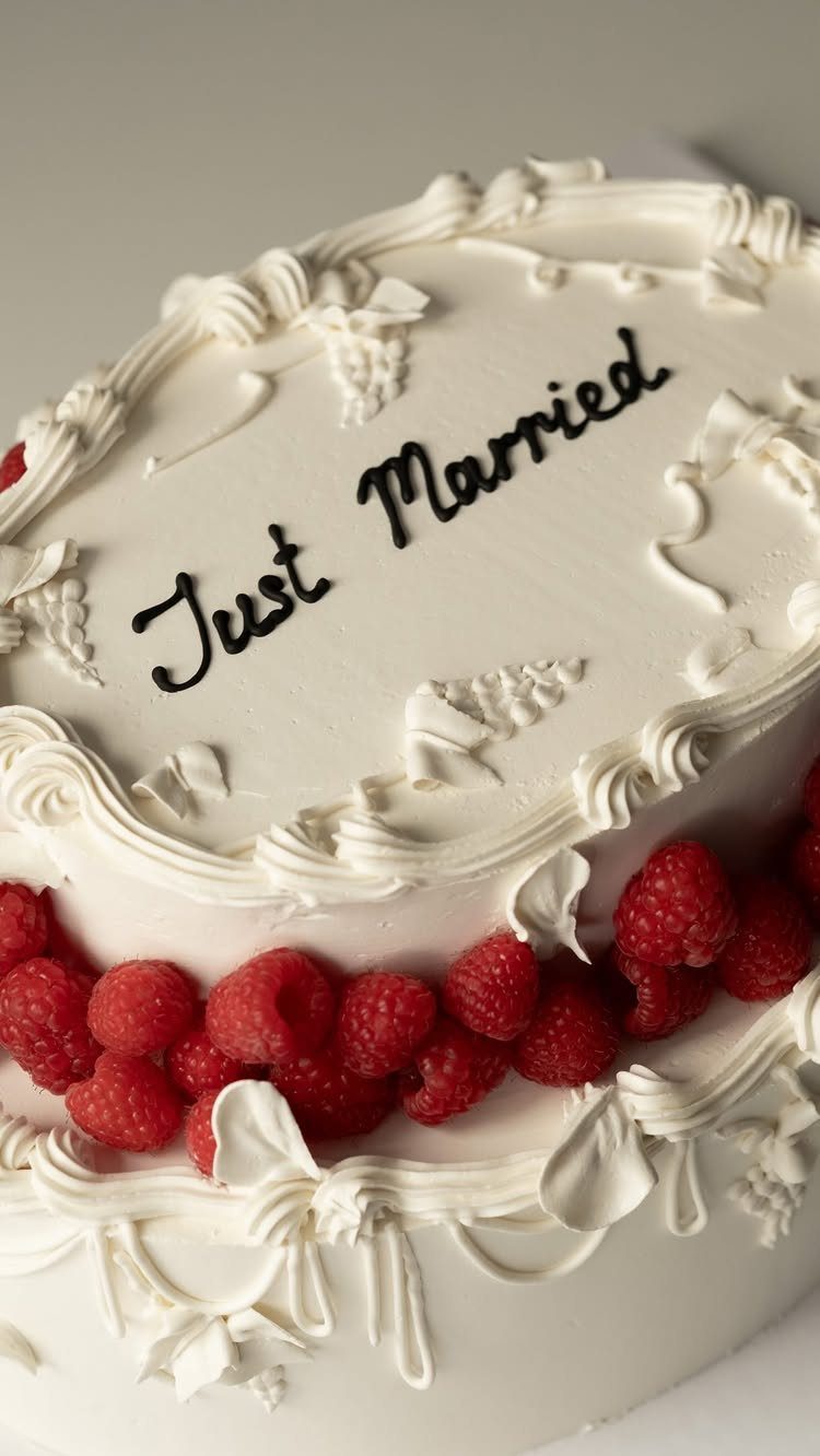 5 Wedding Cake Just Married Ideas for Real Budgets 6 A white frosted wedding cake decorated with red raspberries and the words Just Married in black icing.