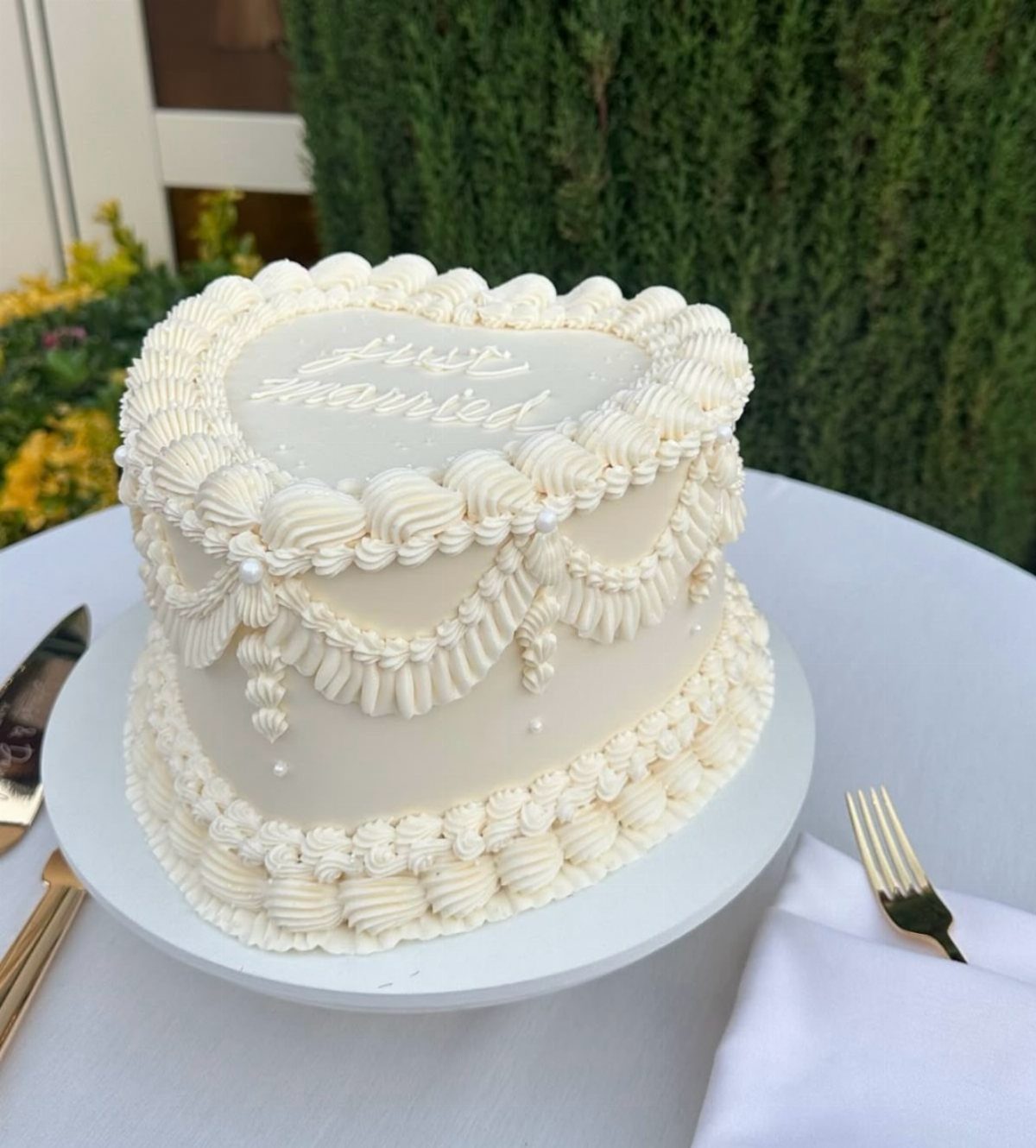 5 Wedding Cake Just Married Ideas for Real Budgets 4 Heart-shaped white buttercream wedding cake with piped ruffles and just married lettering on top.