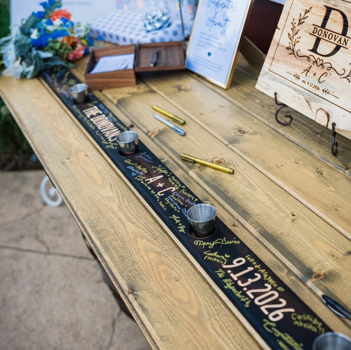 Wooden shot ski with embedded glasses and gold calligraphy on a rustic table