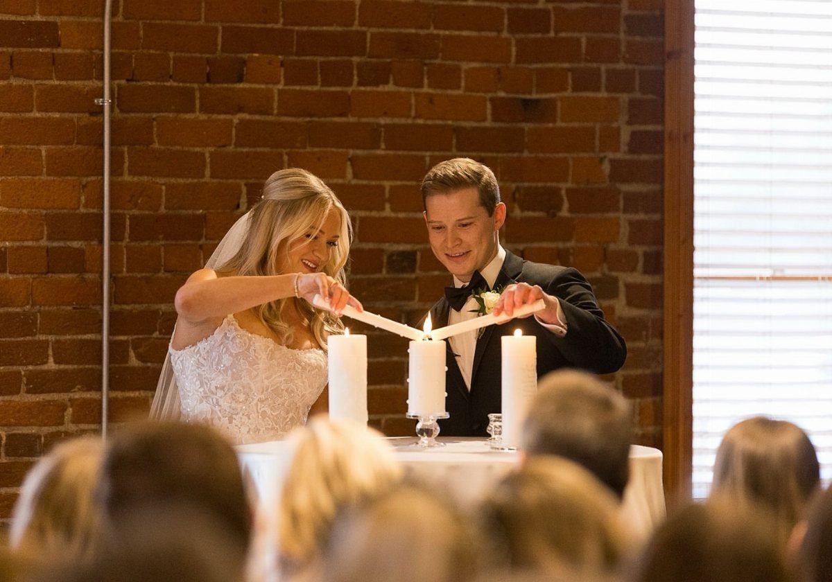 Bride and groom lighting a single unity candle during their wedding ceremony