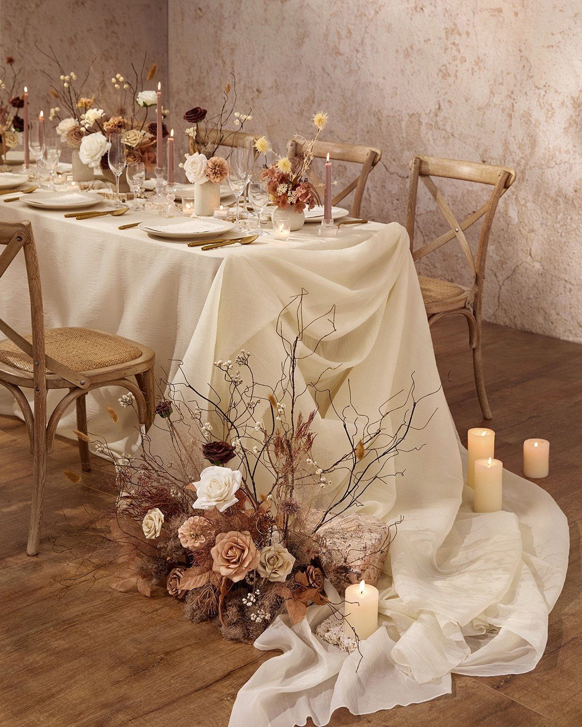 Wedding Decor Brown: How to Use It in 8 Elegant Ways 9 A wedding table setting with cream linens, gold cutlery, and arrangements of dried flowers and branches.