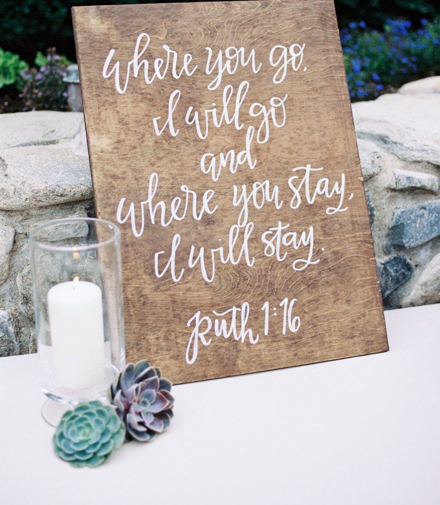 Wedding Decor Quotes: 7 Display Ideas From Letterboard to Acrylic 7 Wooden sign with Ruth 1:16 scripture text, a candle, and succulents on a white table.