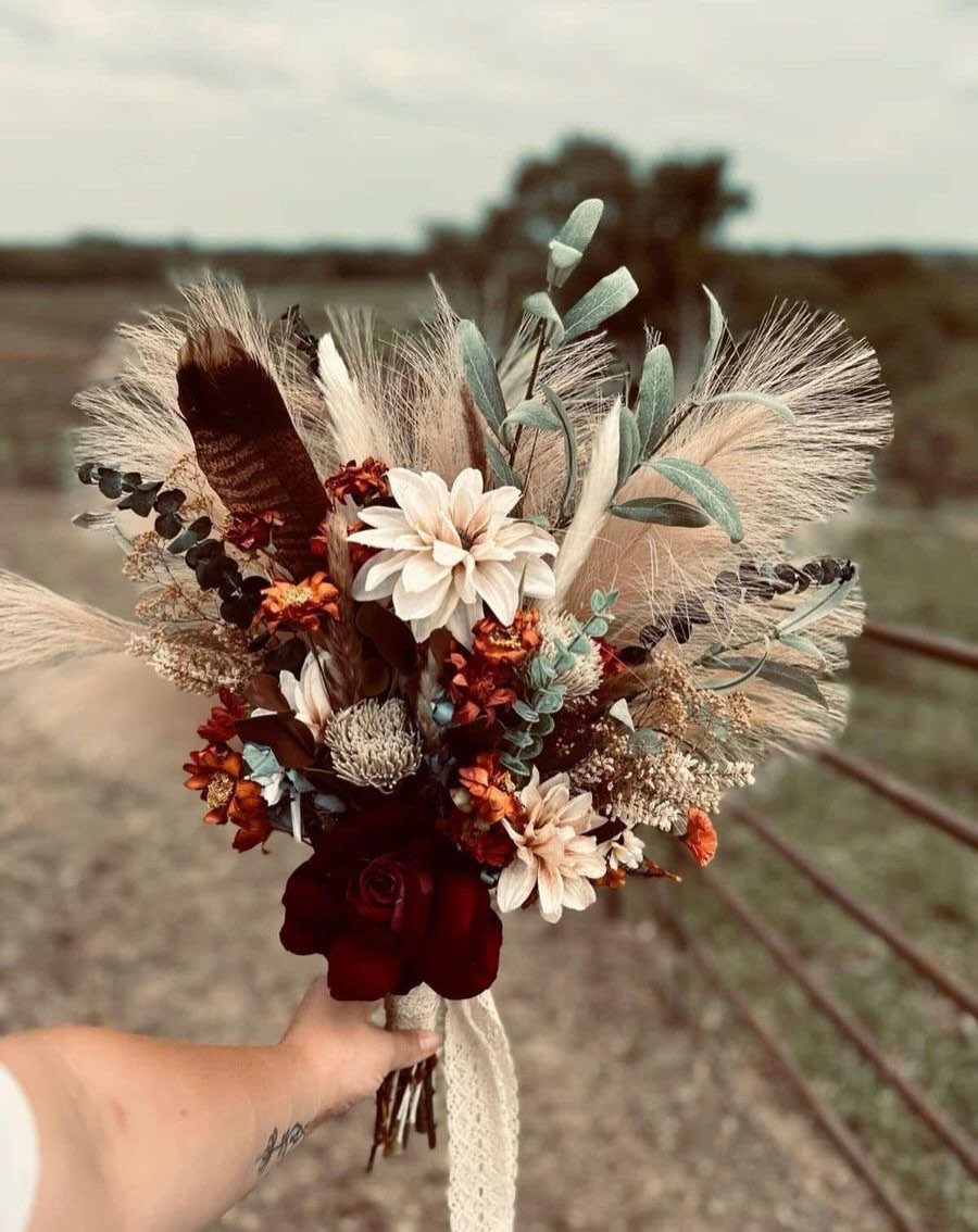 Wedding Decor with Western Style: 21 Ideas from Ranch to Aisle 6 A hand holding a large bouquet of dried pampas grass, dahlias, and red roses outdoors.