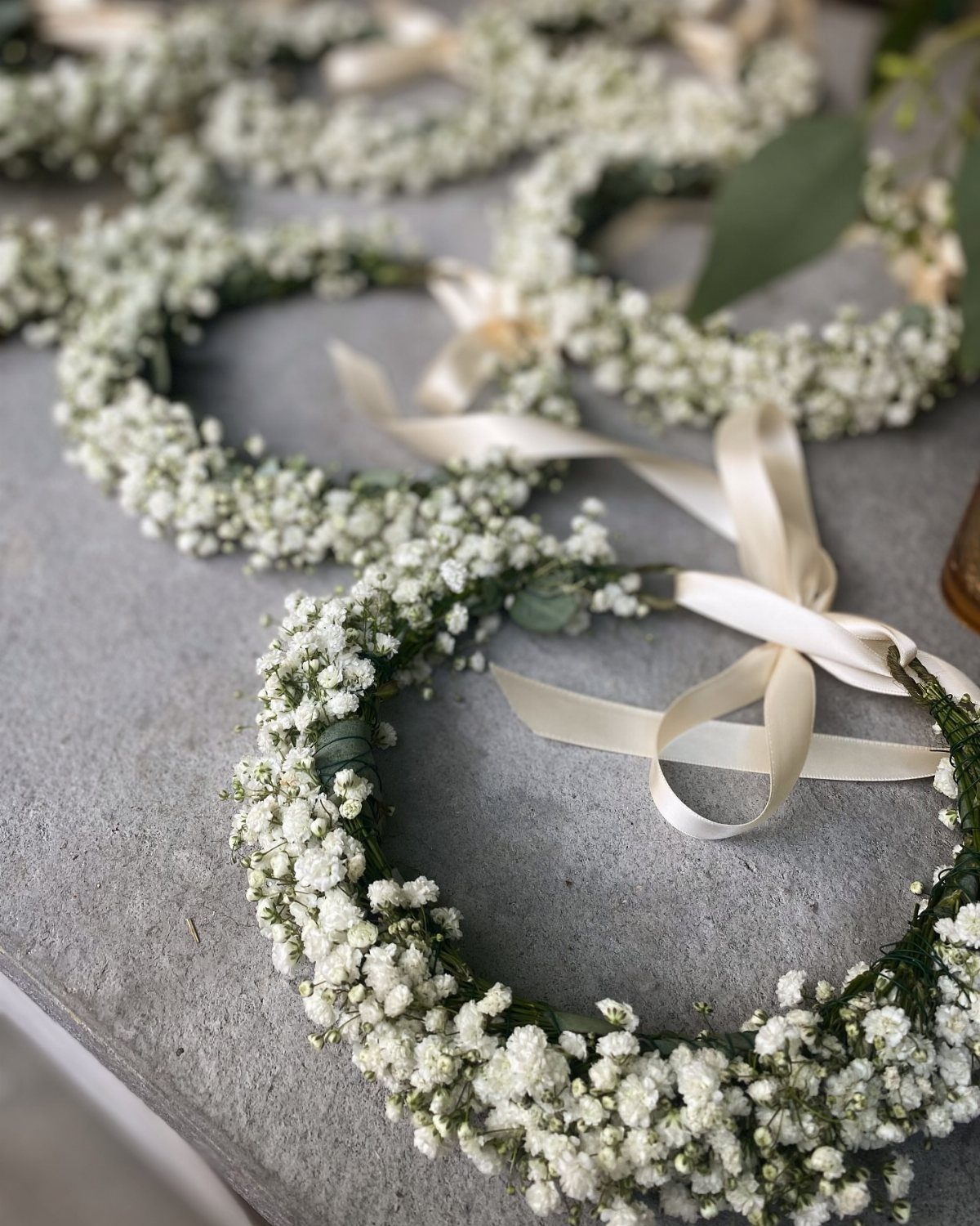 Wedding Decor with Western Style: 21 Ideas from Ranch to Aisle 18 White baby's breath floral crowns with cream satin ribbons resting on a grey stone surface.