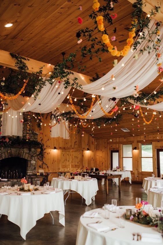 Wedding Decor with Western Style: 21 Ideas from Ranch to Aisle 10 White fabric swags and floral garlands draped across a rustic wooden ceiling with string lights.