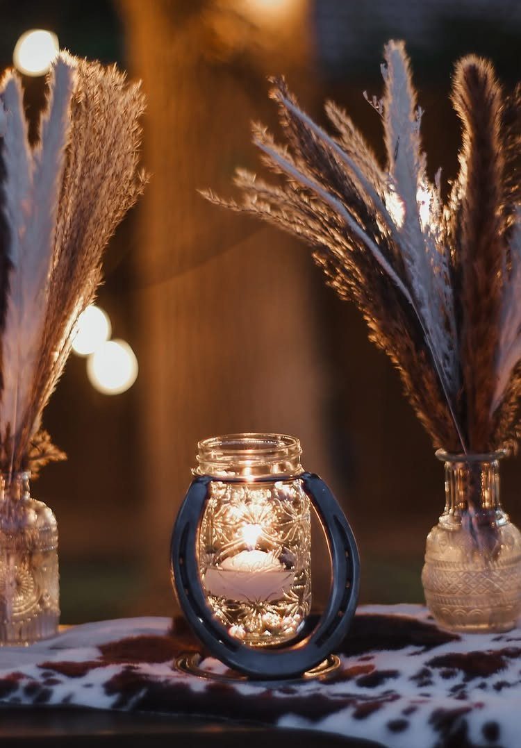 Wedding Decor with Western Style: 21 Ideas from Ranch to Aisle 15 A lit candle in a glass jar framed by a metal horseshoe on a cowhide rug.