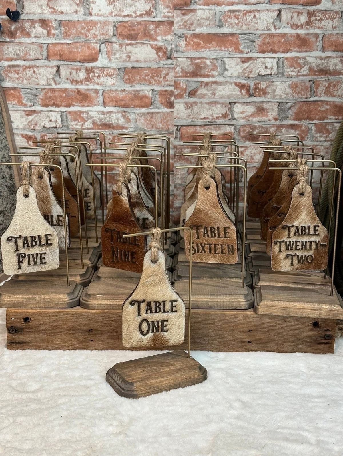 Wedding Decor with Western Style: 21 Ideas from Ranch to Aisle 8 Cowhide-shaped wooden table number signs on metal stands arranged on rustic wooden crates.