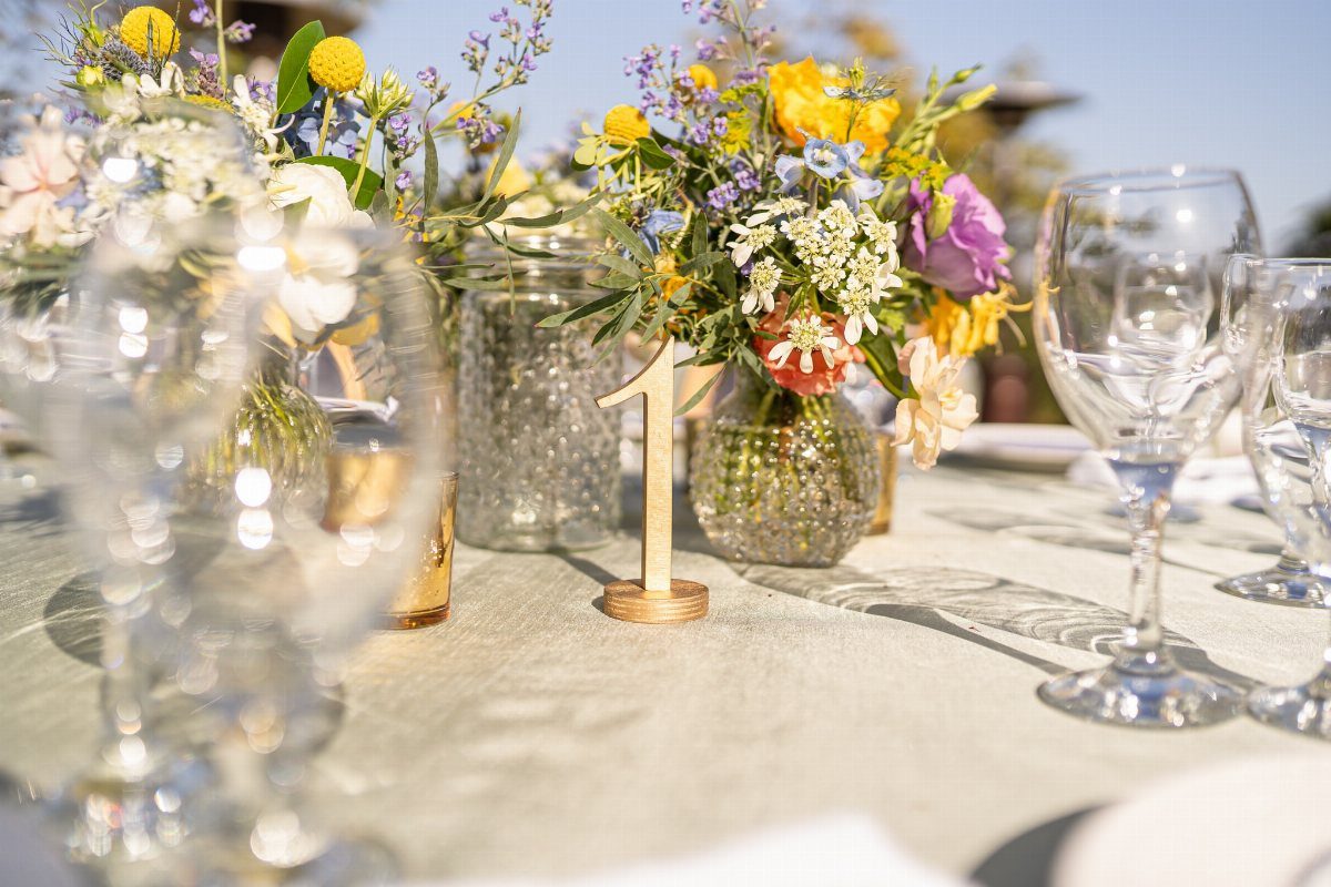 Wedding Decor with Western Style: 21 Ideas from Ranch to Aisle 14 Wildflower arrangements in glass vases set on a table with wine glasses outdoors.