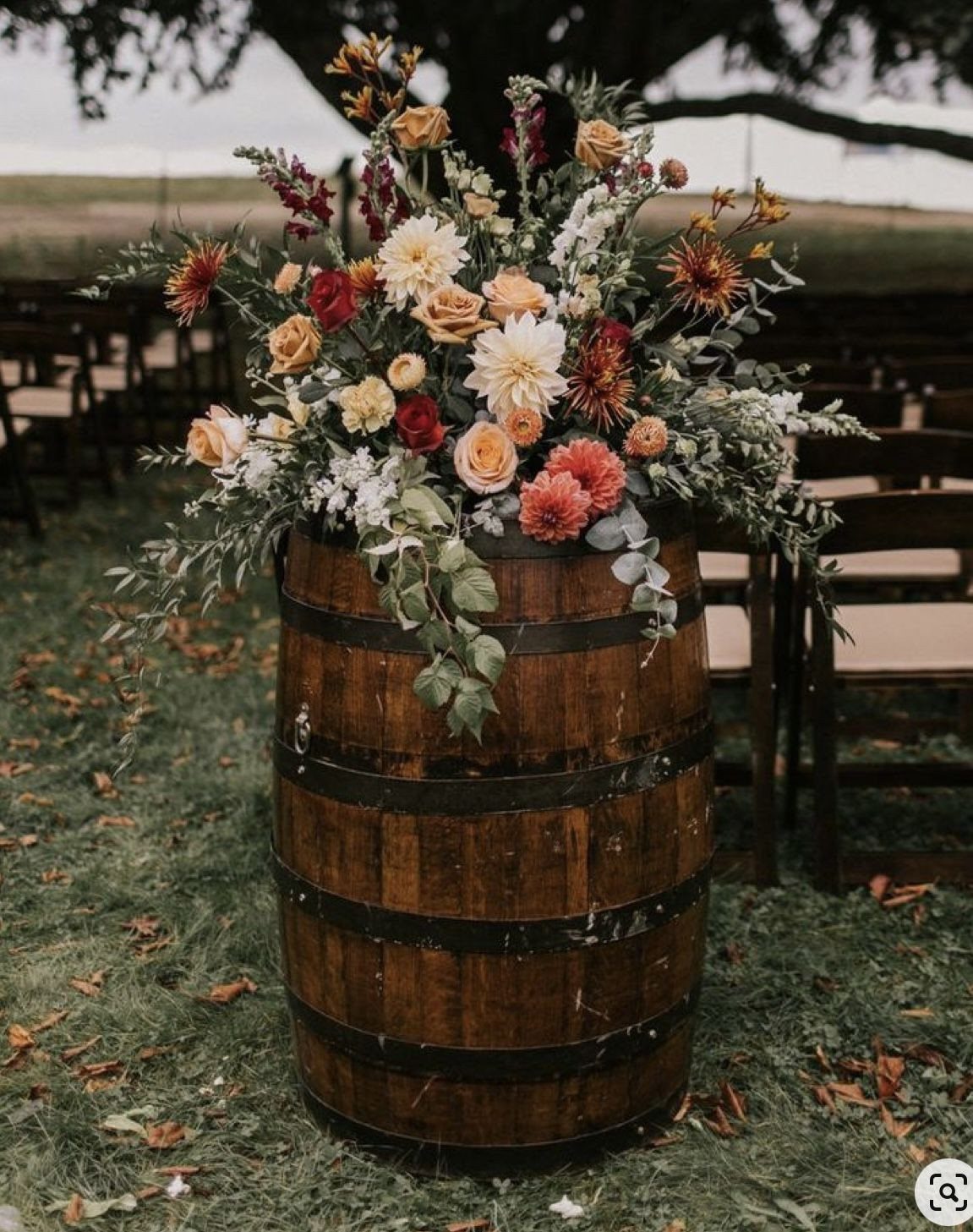 Wedding Decor with Western Style: 21 Ideas from Ranch to Aisle 5 A wooden barrel decorated with a large, colorful floral arrangement on green grass.