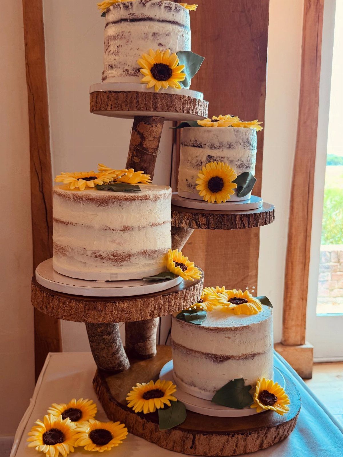 Wedding Decor with Western Style: 21 Ideas from Ranch to Aisle 19 Four sunflower decorated naked cakes resting on rustic wooden slice cake stands.