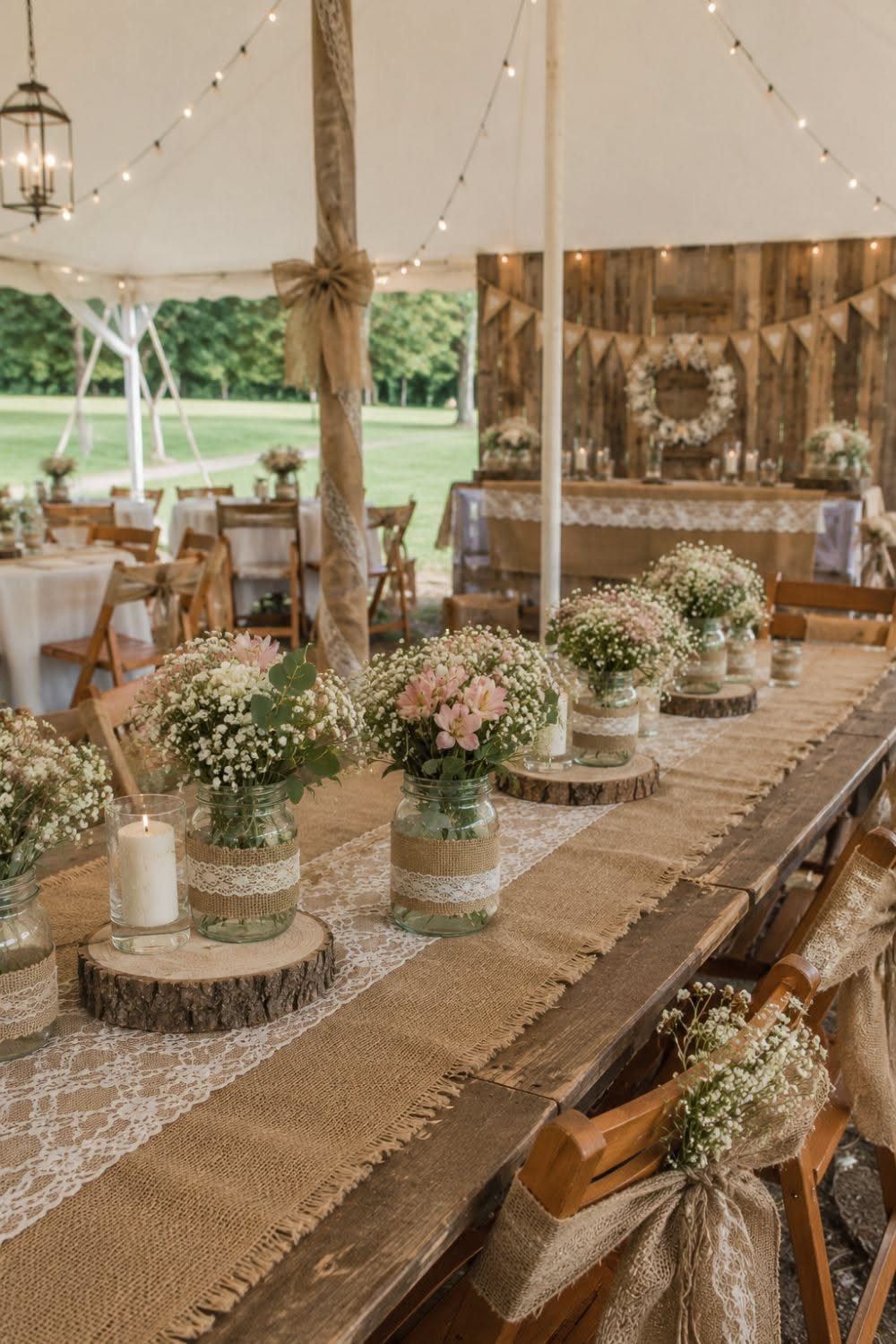 Wedding Decor with Western Style: 21 Ideas from Ranch to Aisle 9 Long wooden table set with burlap lace runners, mason jar floral arrangements, and candles under a tent.