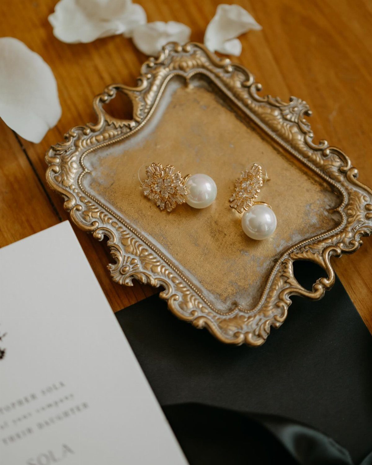Wedding Detail Shots: 21 Ideas for Your Photographer 15 Gold and pearl earrings resting on an ornate vintage tray surrounded by white petals.