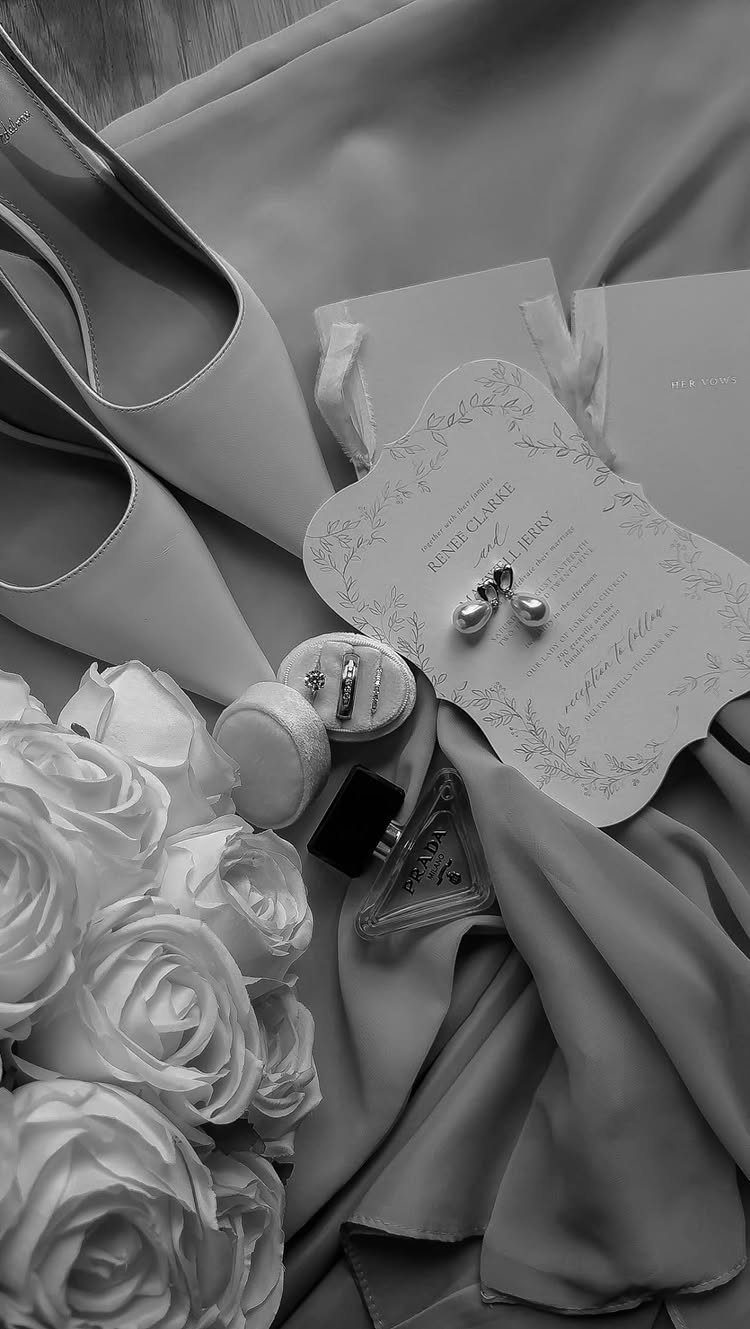 Wedding Detail Shots: 21 Ideas for Your Photographer 2 White roses, wedding shoes, an invitation, and rings arranged in a flat lay on fabric.