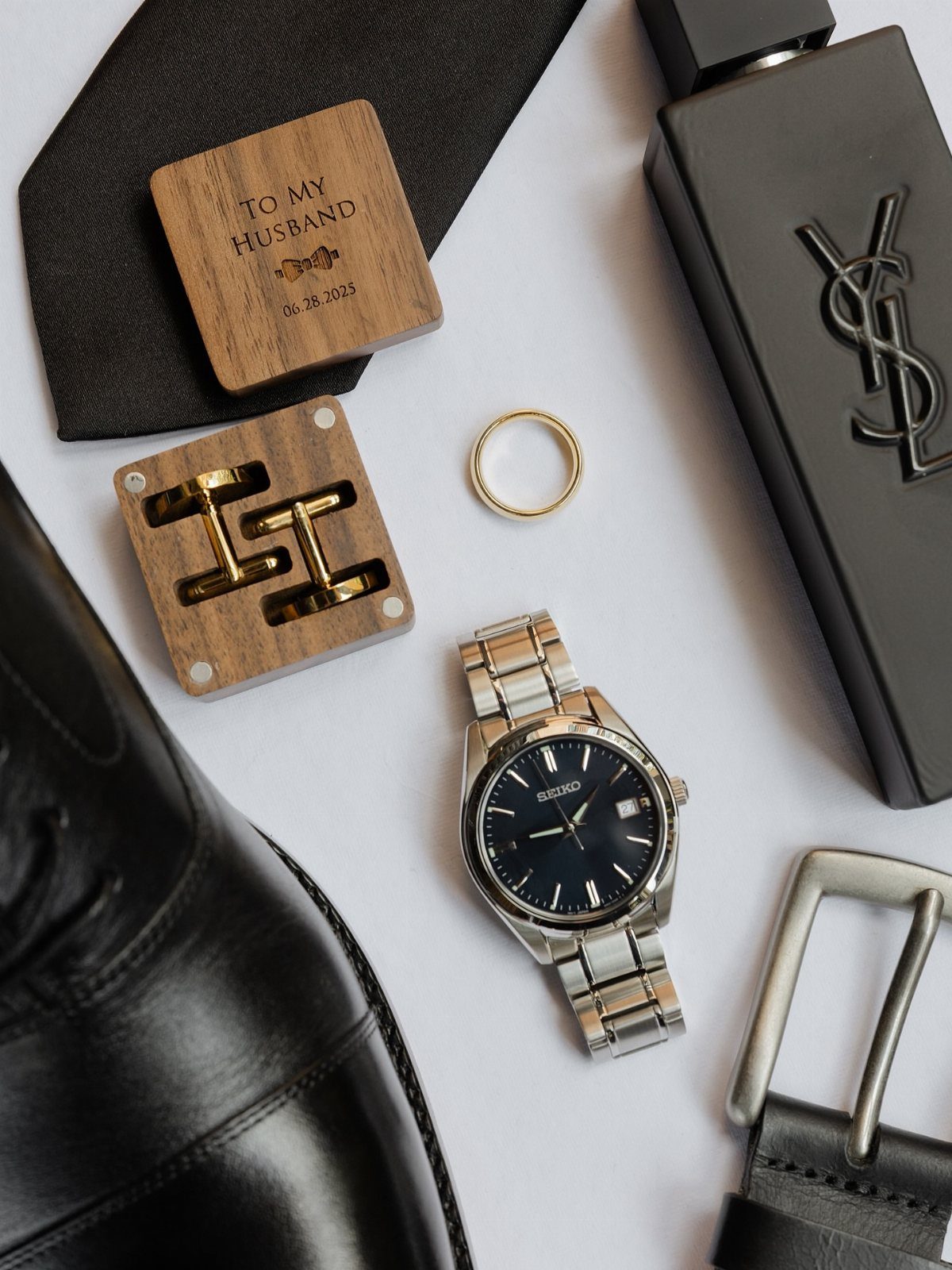 Wedding Detail Shots: 21 Ideas for Your Photographer 7 Groom's accessories including a watch, ring, cufflinks, tie, and leather shoe arranged on a white surface.