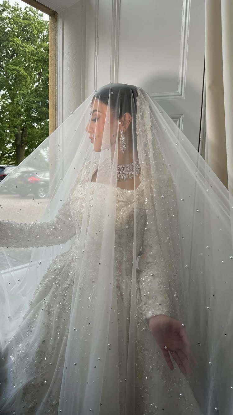 Wedding Detail Shots: 21 Ideas for Your Photographer 10 A bride wearing a beaded white wedding dress and a long pearl-embellished veil.
