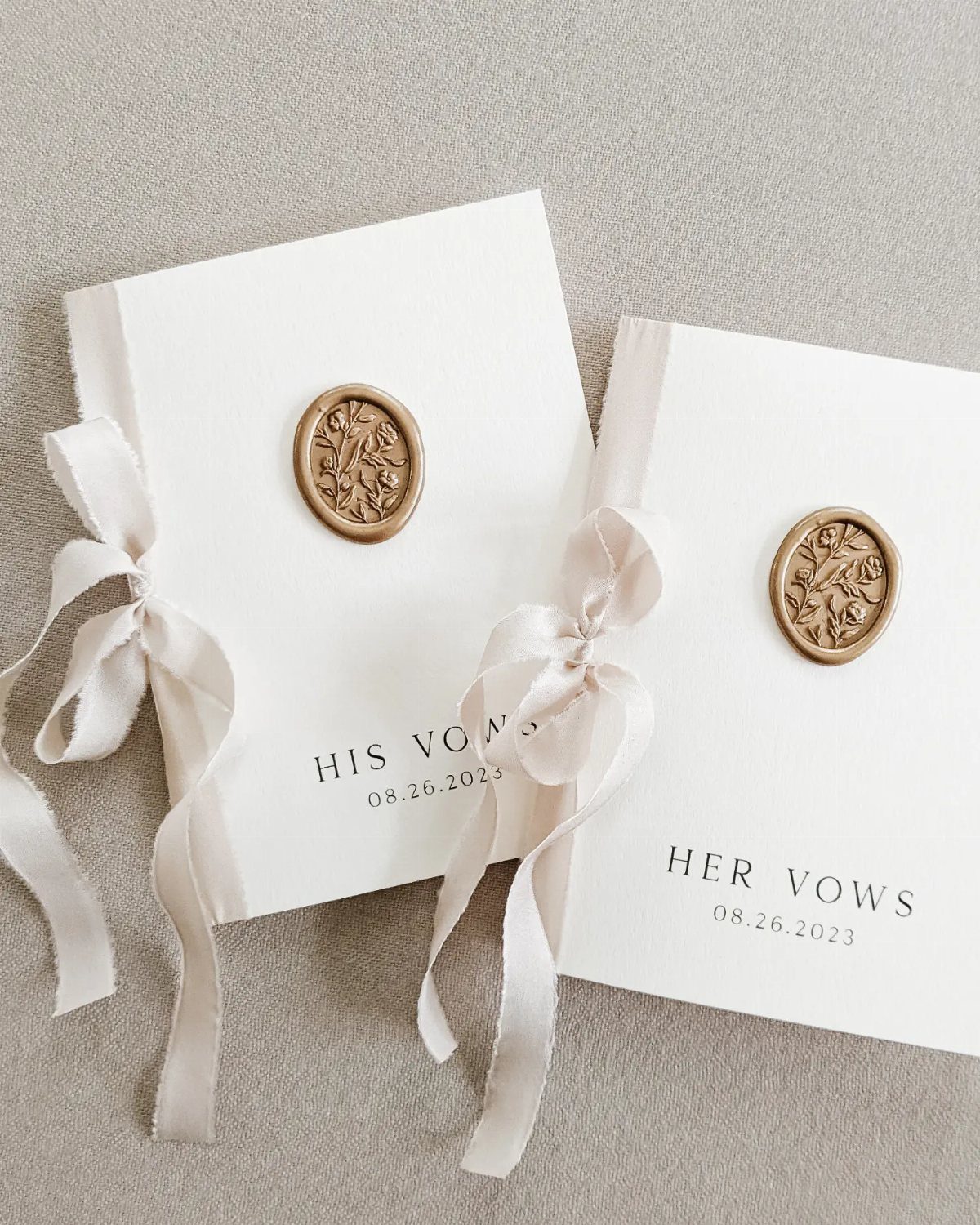 Wedding Detail Shots: 21 Ideas for Your Photographer 13 Two white vow books with gold wax seals and cream ribbons on a neutral background.