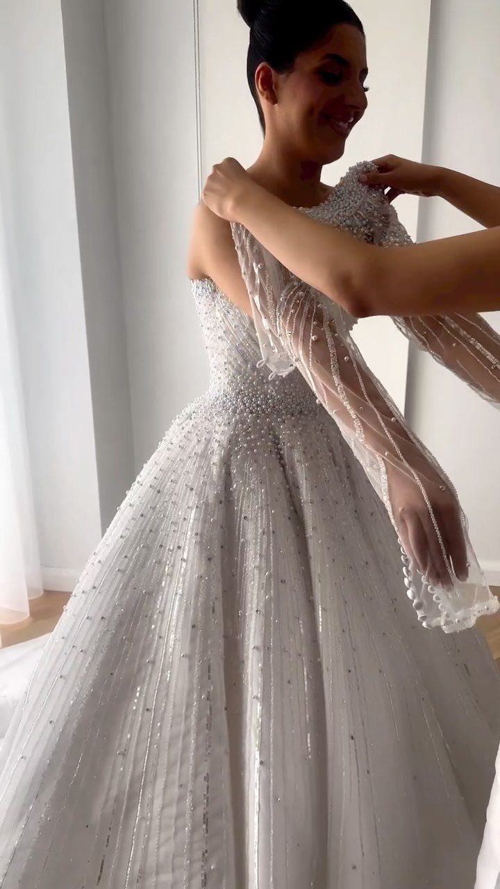 Woman wearing a white A-line wedding dress with intricate silver beading and sequins.