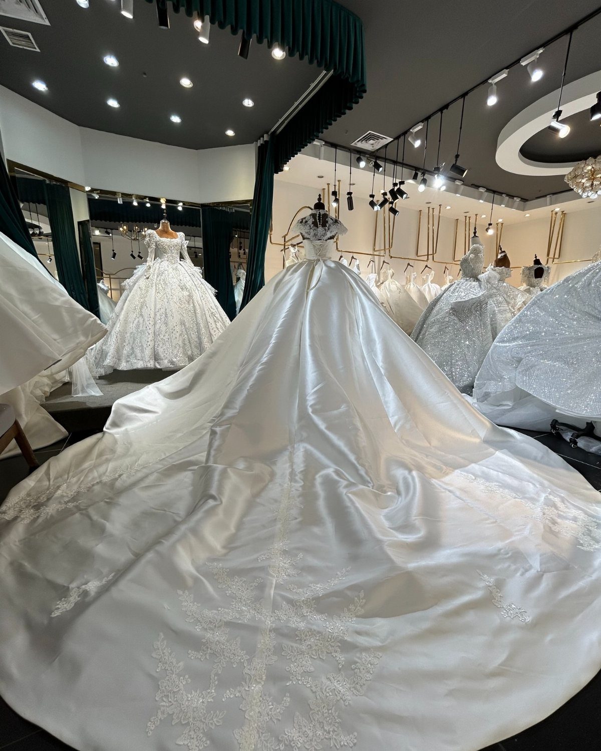 White satin A-line wedding dress with a long train on a mannequin.