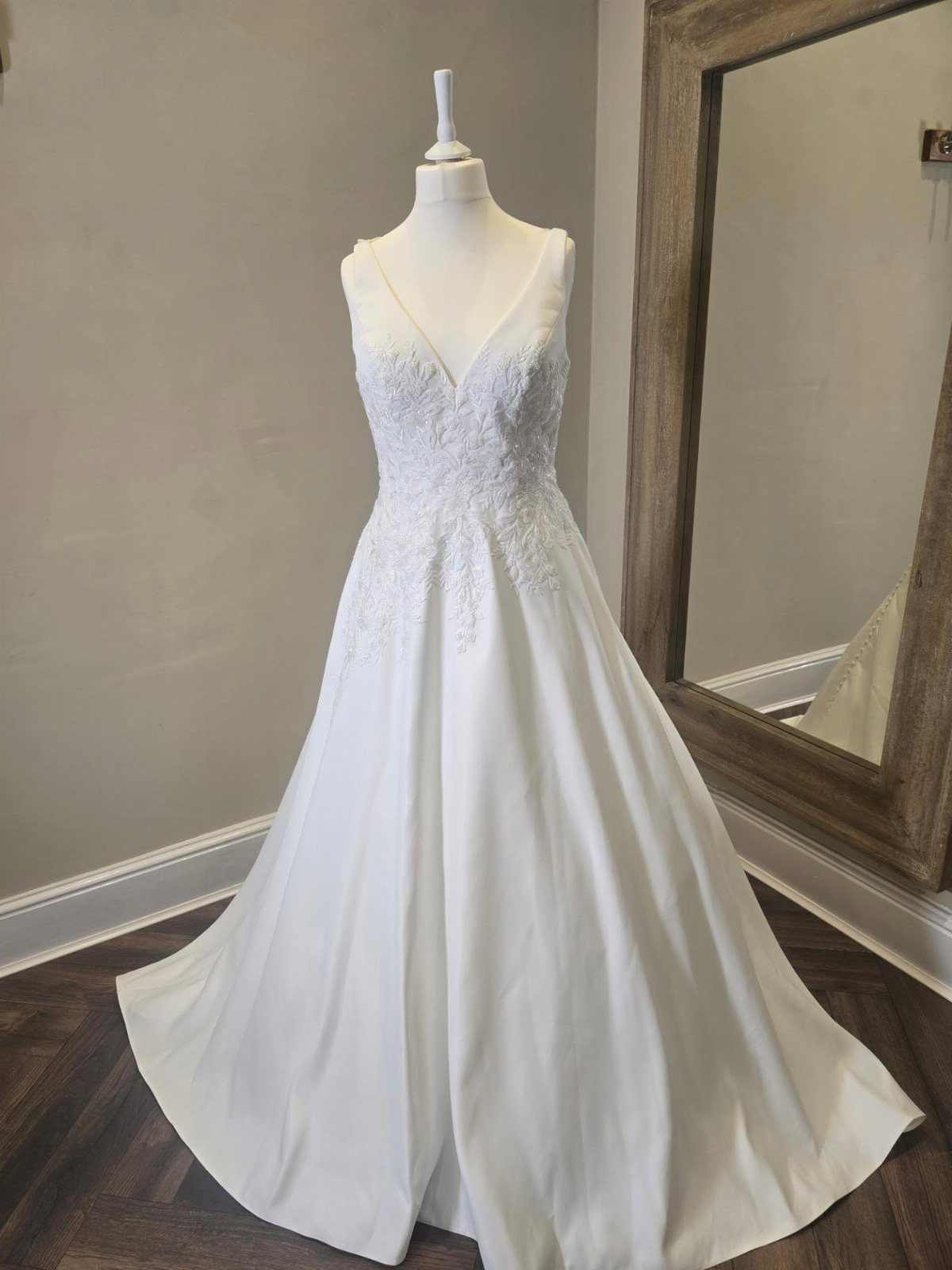 White A-line wedding dress with lace bodice and satin skirt on a mannequin.