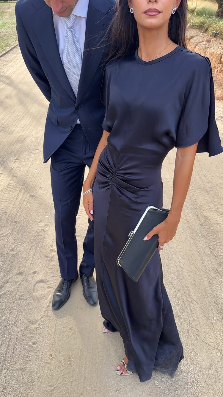 Woman in navy blue satin maxi dress and man in navy suit outdoors