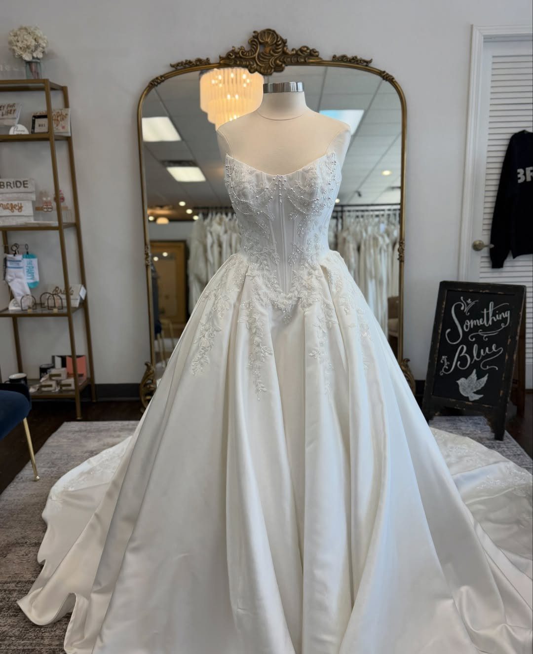 White satin wedding gown with lace bodice and full skirt on a mannequin.