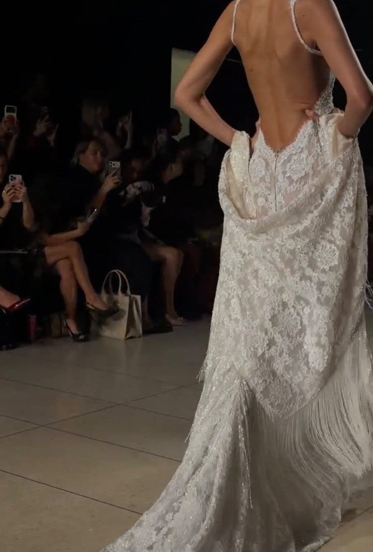 Tight Lace Wedding Dresses in 25 Beautiful Styles 7 Woman wearing a white backless lace wedding dress with a long train on a runway.