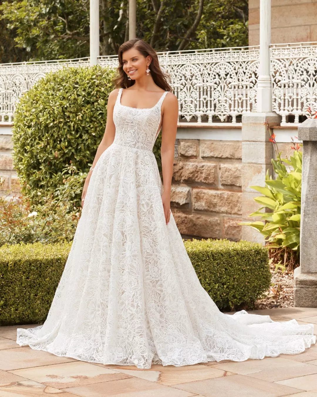 Tight Lace Wedding Dresses in 25 Beautiful Styles 17 Woman in a white lace wedding dress with a square neckline standing outdoors.