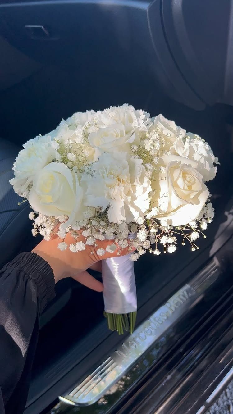 Wedding Flower Trends: 36 Ideas from Jewel Tones to Arches 7 White rose and baby's breath bridal bouquet held against a dark car interior.