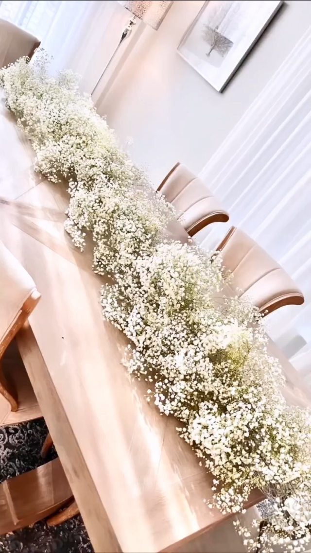 Wedding Flower Trends: 36 Ideas from Jewel Tones to Arches 24 White baby's breath floral runner stretching across a light wooden dining table.