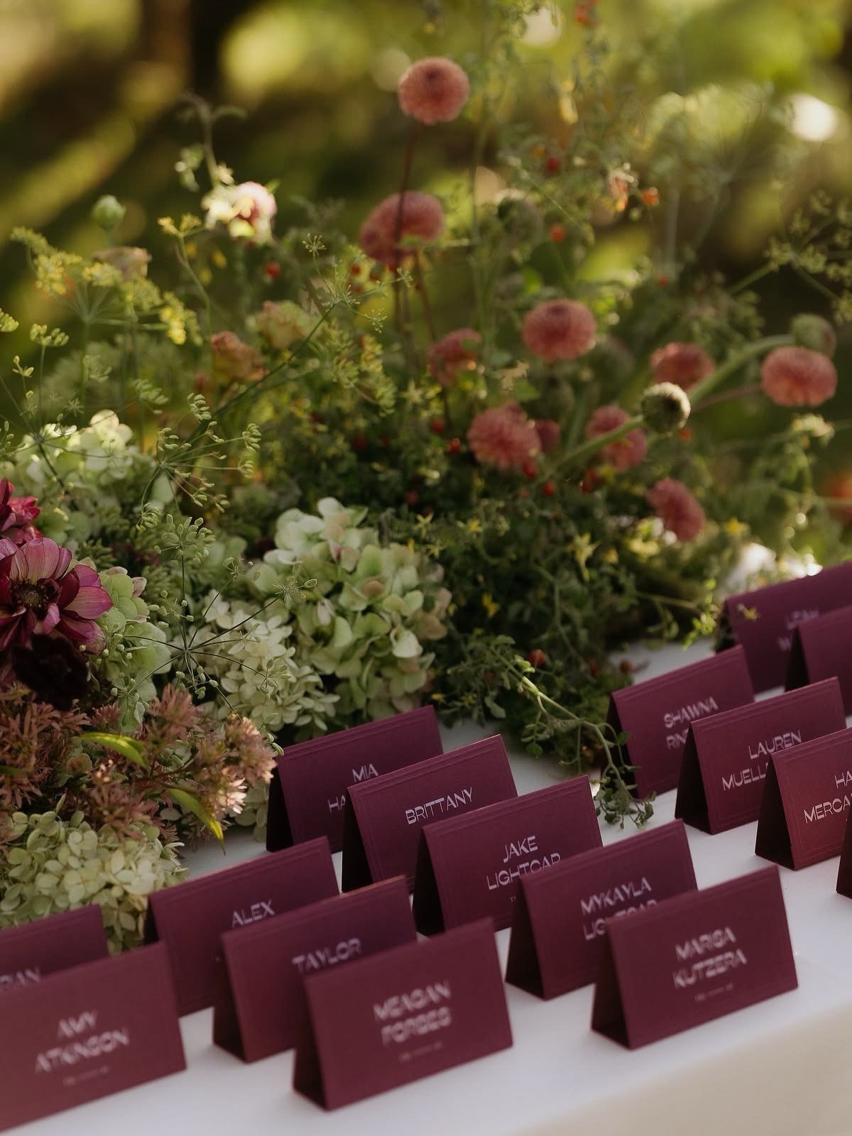 Wedding Flower Trends: 36 Ideas from Jewel Tones to Arches 9 Burgundy place cards and floral arrangements with deep red and green foliage.