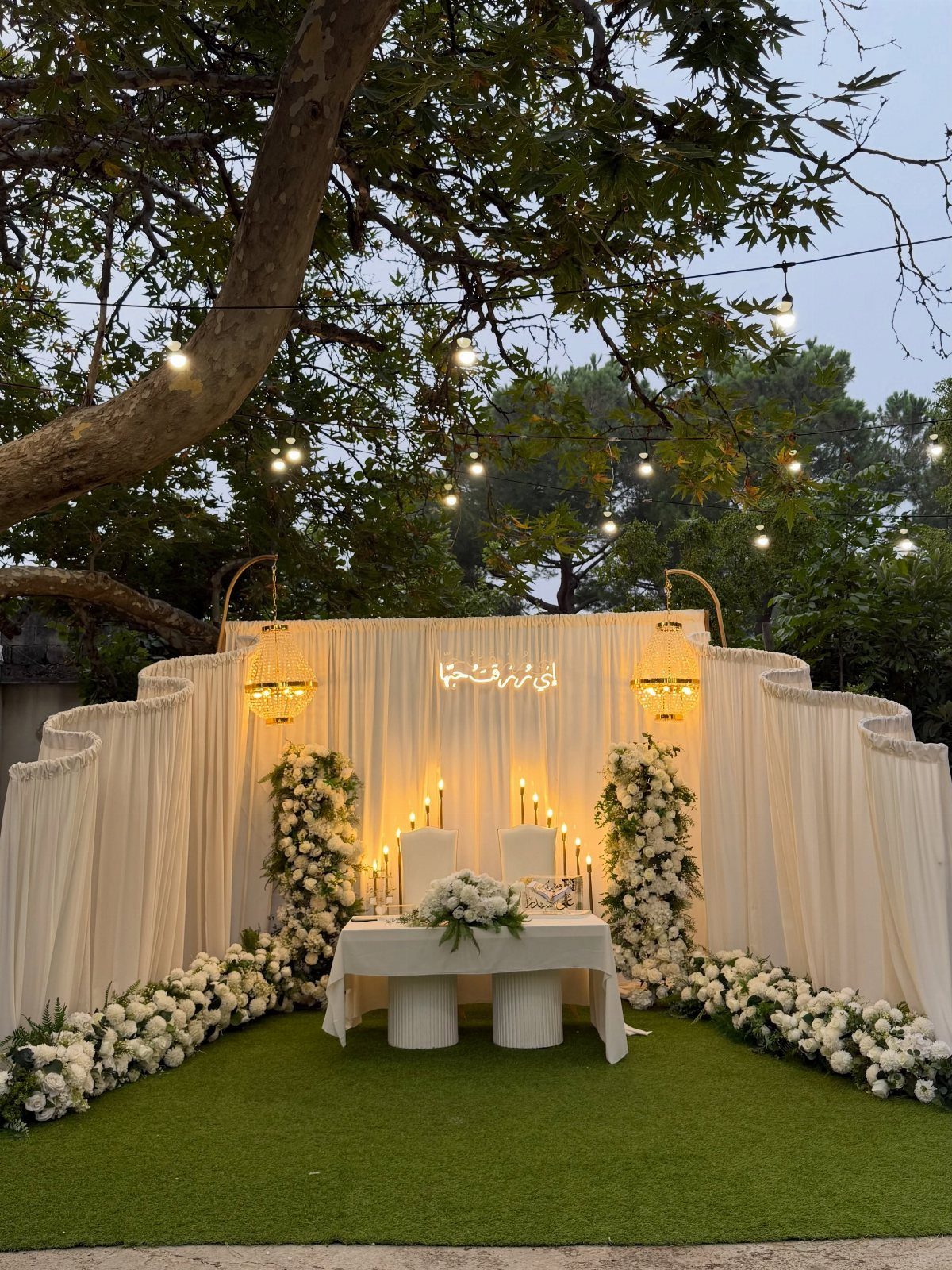 Wedding Flower Trends: 36 Ideas from Jewel Tones to Arches 18 White floral arrangements and draped backdrop at an outdoor wedding ceremony altar.
