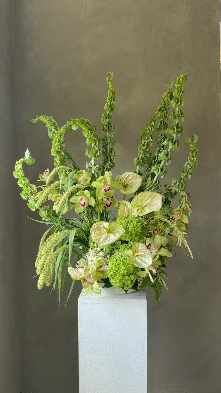 Wedding Flower Trends: 36 Ideas from Jewel Tones to Arches 28 Green floral arrangement with anthuriums and bells of Ireland on a white pedestal.
