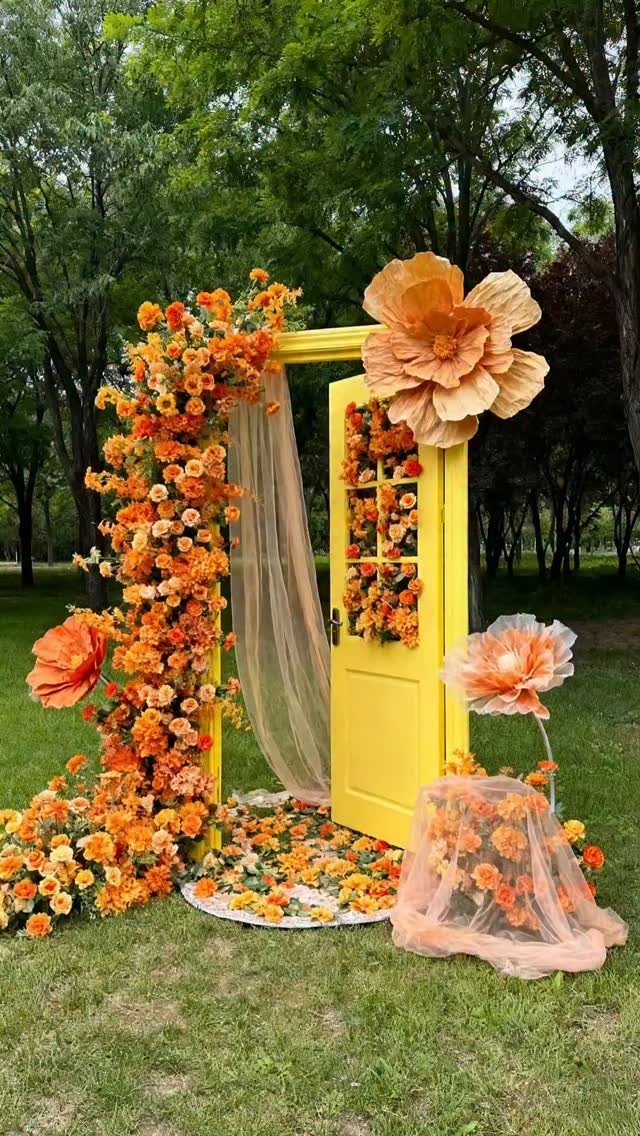 Wedding Flower Trends: 36 Ideas from Jewel Tones to Arches 3 Yellow door frame decorated with orange flowers and oversized floral art in a park