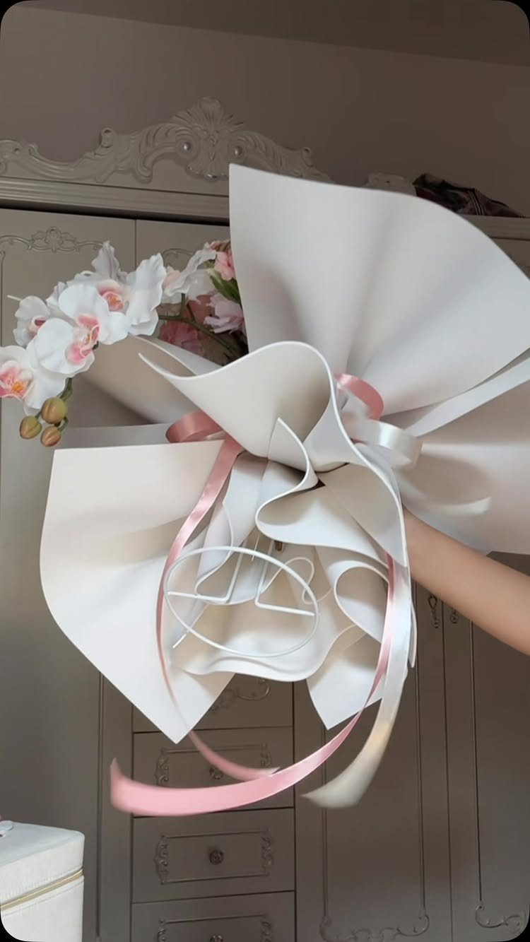 Wedding Flower Trends: 36 Ideas from Jewel Tones to Arches 36 Bouquet of white and pink flowers wrapped in sculptural white paper with pink ribbon.