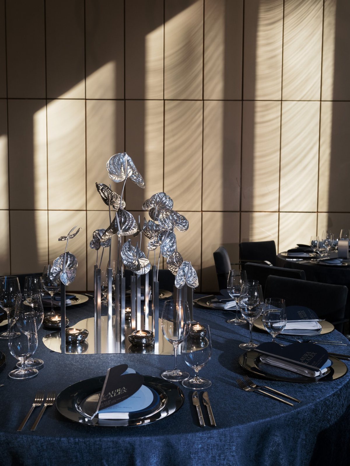Wedding Flower Trends: 36 Ideas from Jewel Tones to Arches 19 Chrome metallic flower sculptures in a mirrored vase on a blue wedding table.