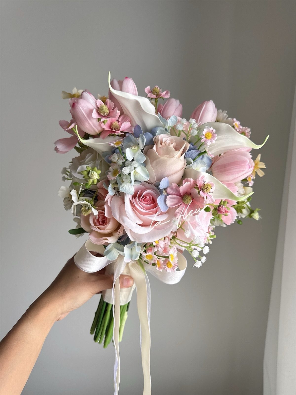 Wedding Flower Trends: 36 Ideas from Jewel Tones to Arches 15 Bridal bouquet with soft pink roses, tulips, and blue accents tied with white ribbon.