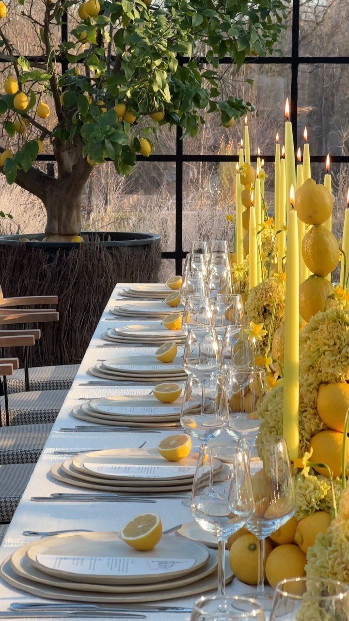 Wedding Flower Trends: 36 Ideas from Jewel Tones to Arches 25 Dining table centerpiece with yellow flowers, lemons, and tall yellow candles.