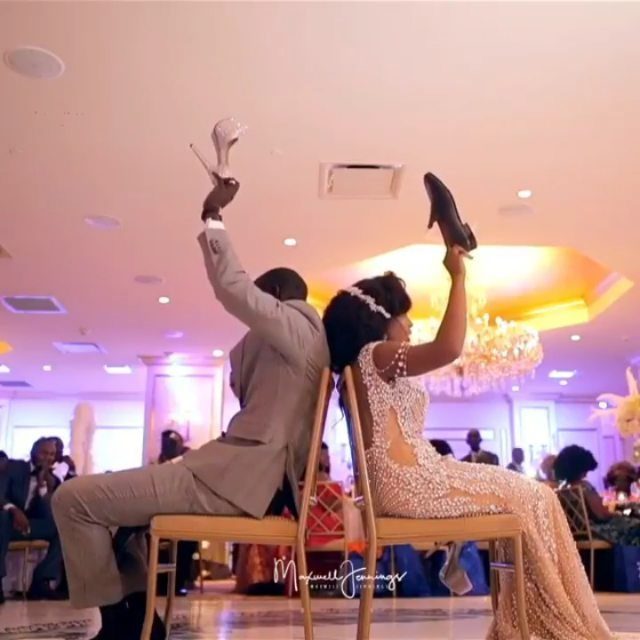 13 Wedding Games Table Ideas Your Guests Will Actually Play 2 Bride and groom sitting back-to-back holding up shoes to play a wedding game.