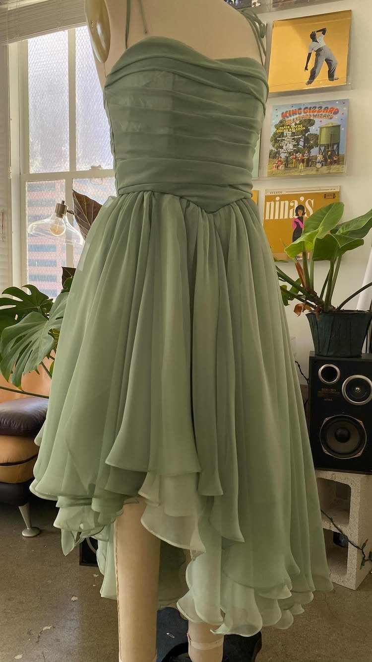 19 Wedding Guest Dress Ideas for Every Season and Style 20 Sage green strapless high-low dress with ruched bodice on a mannequin.