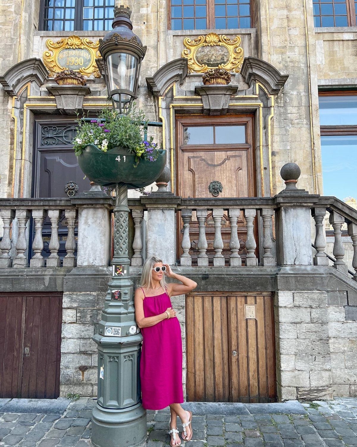 19 Wedding Guest Dress Ideas for Every Season and Style 19 Woman in a magenta midi dress posing by a street lamp and stone building.