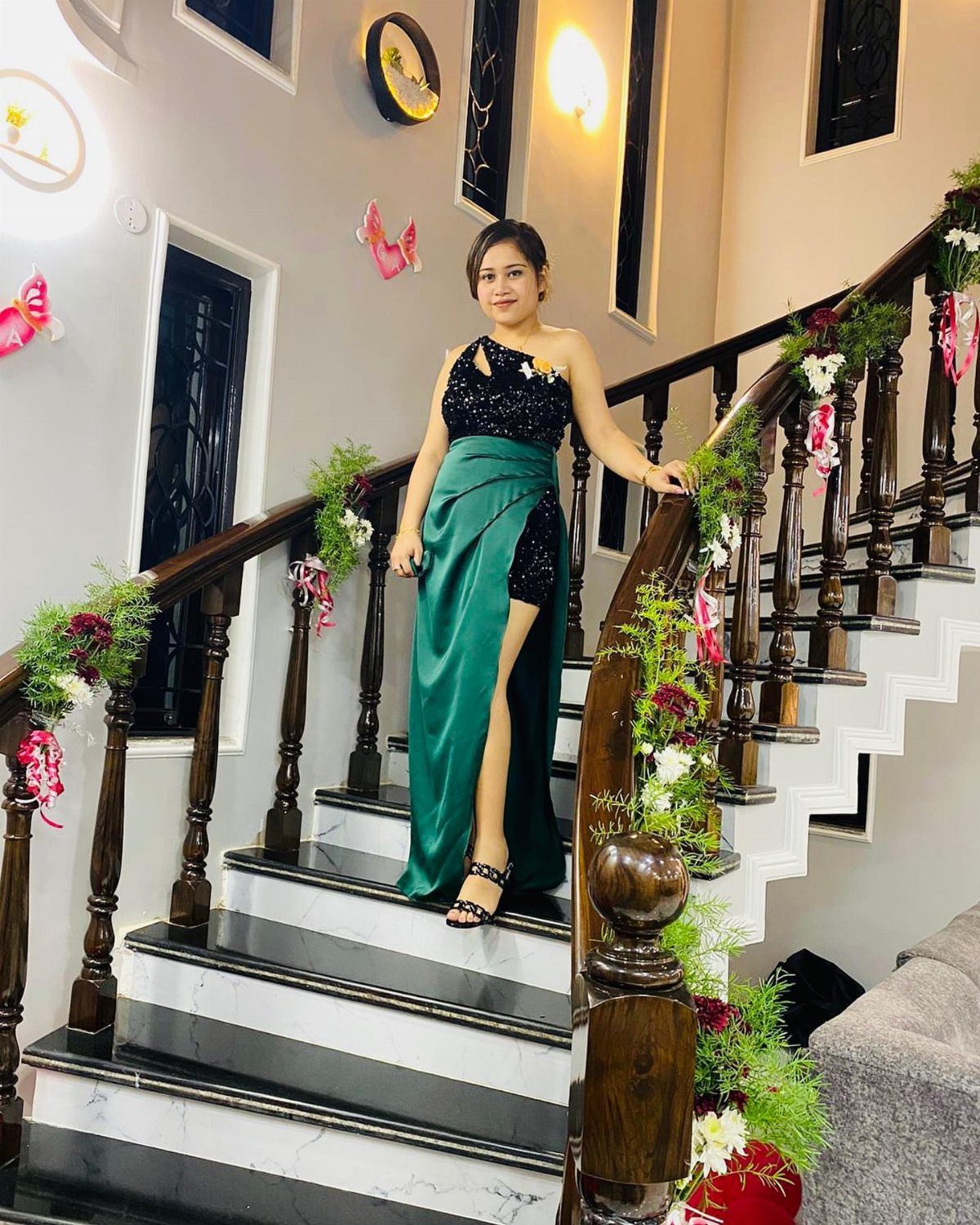 19 Wedding Guest Dress Ideas for Every Season and Style 16 Woman in a black and emerald green two-tone gown posing on a staircase.