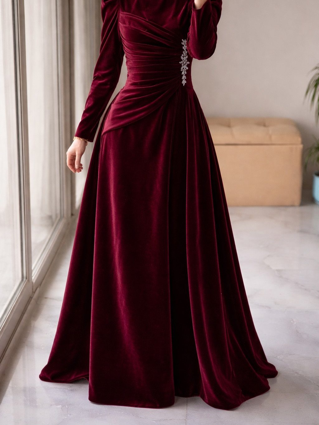 19 Wedding Guest Dress Ideas for Every Season and Style 5 Burgundy velvet long-sleeved gown with ruched waist and silver embellishment on a person.