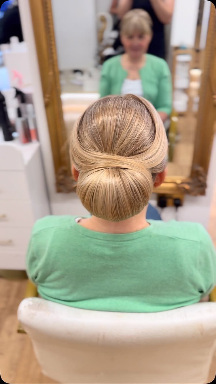 17 Wedding Guest Hairstyles Up: From Curled Updos to Bubble Braids 3 Blonde hair styled in a smooth, elegant low chignon updo seen from behind.