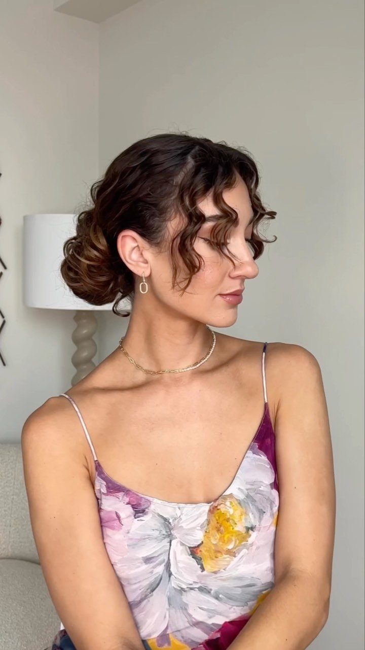 17 Wedding Guest Hairstyles Up: From Curled Updos to Bubble Braids 2 Woman with dark curly hair in a textured low updo with face-framing curls.