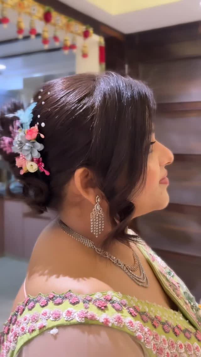 17 Wedding Guest Hairstyles Up: From Curled Updos to Bubble Braids 9 Woman in profile with a dark hair updo decorated with colorful flowers and silver jewelry.