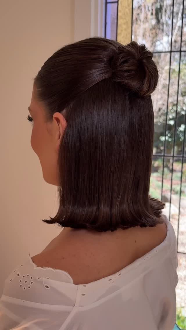 17 Wedding Guest Hairstyles Up: From Curled Updos to Bubble Braids 14 Woman with dark hair styled in a half-up bun and straight shoulder-length hair.