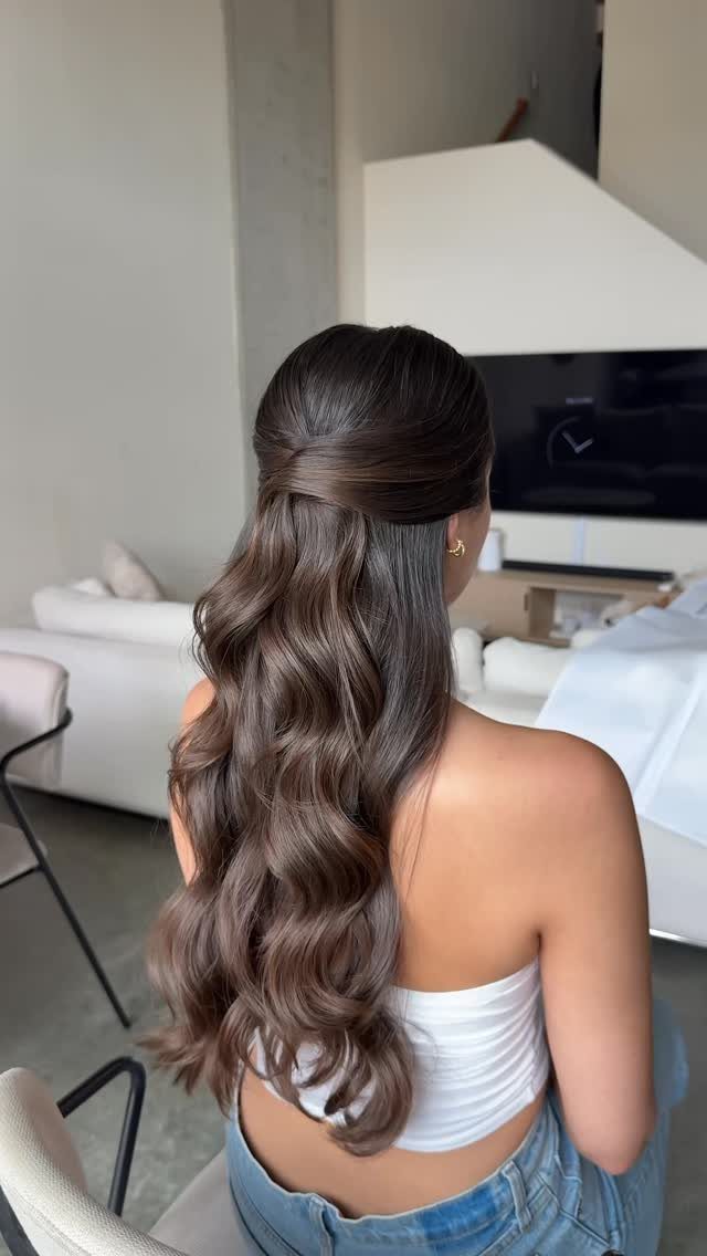17 Wedding Guest Hairstyles Up: From Curled Updos to Bubble Braids 15 Woman with long wavy brown hair in a half-up, half-down hairstyle.