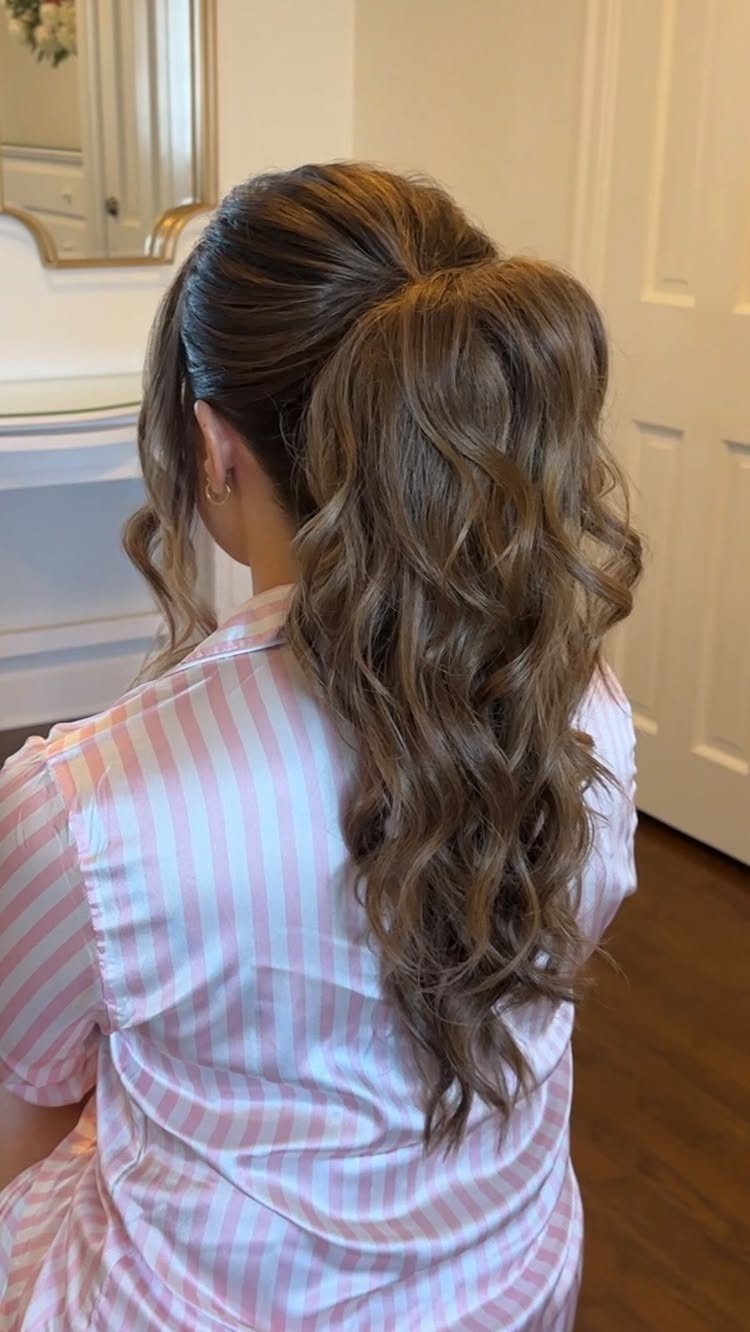 17 Wedding Guest Hairstyles Up: From Curled Updos to Bubble Braids 17 Long wavy brown hair styled in a voluminous high ponytail on a woman wearing pink stripes.