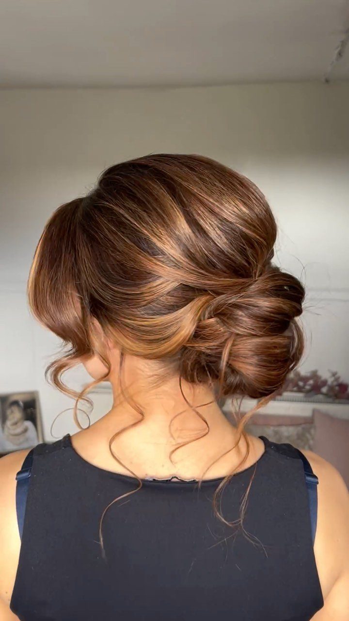 17 Wedding Guest Hairstyles Up: From Curled Updos to Bubble Braids 6 Woman with a low textured bun and curled side tendrils framing her neck.