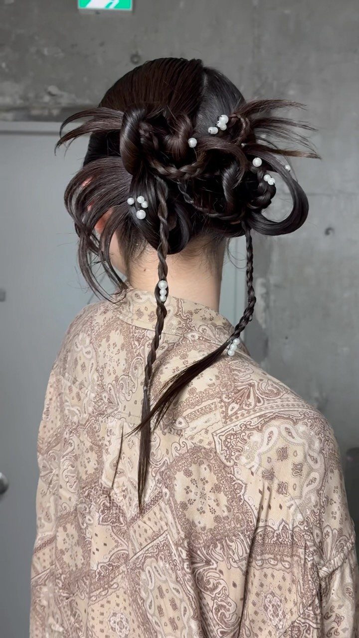 17 Wedding Guest Hairstyles Up: From Curled Updos to Bubble Braids 16 Intricate sculptural dark hair updo with large loops and pearl accents on a person.